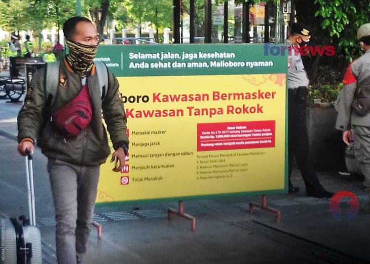 SEORANG wisatawan mendorong koper roda berjalan kaki melewati pengamanan Presiden RI Joko Widodo saat berkunjung ke Yogyakarta pada 1 Maret 2021. (foto fornews.co/adam)
