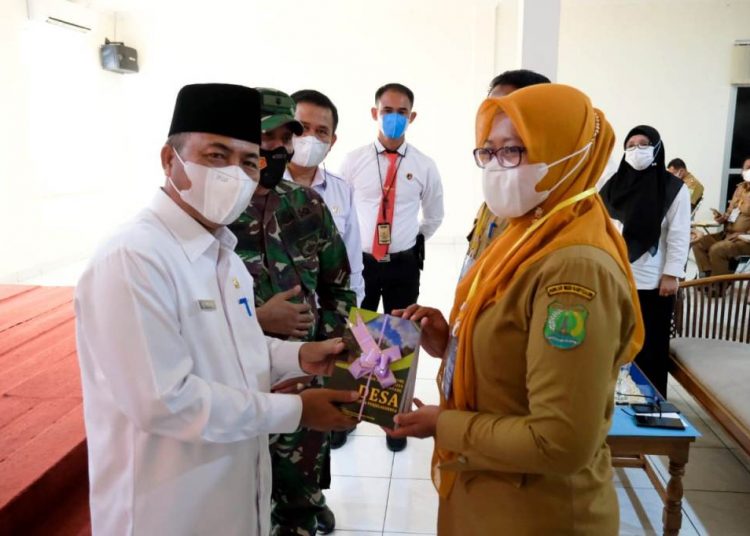 Sekda Muba Apriyadi menyerahkan buku tentang pemerintahan desa kepada salah satu peserta Bimtek Kepala Desa dan Perangkat Desa di Muba, Senin (5/4/2021). (fornews.co/humas pemkab muba)