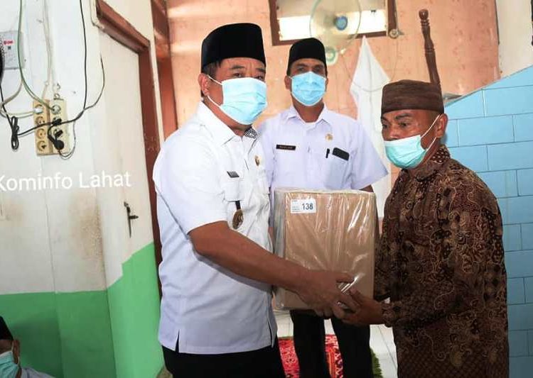 Bupati Lahat Cik Ujang saat menyerahkan bantuan Alquran kepada pengurus Masjid Al-Amin di Desa Lubuk Atung, Kecamatan Pseksu, Jumat (9/4/2021). (fornews.co/kominfo lahat)