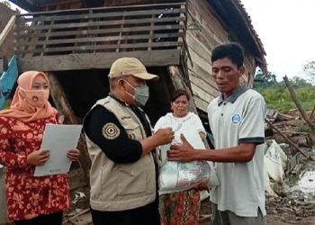 Kepala Dinsos Muba Ahmad Nasuhi saat menyerahkan bantuan kepada Kusnadi yang rumahnya roboh dihantam angin puting beliung, Selasa (20/4/2021). (fornews.co/humas pemkab muba)