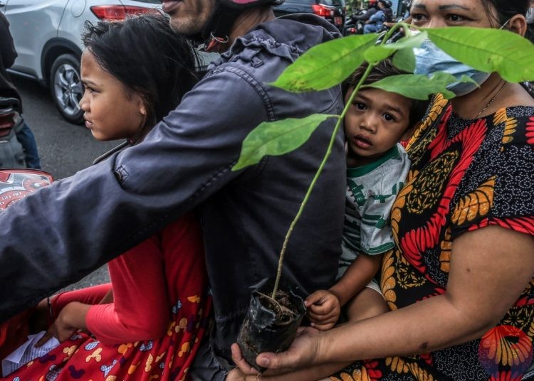 Pengendara membawa bibit yang dibagikan. (matakamera/fornews.co/mushaful imam)