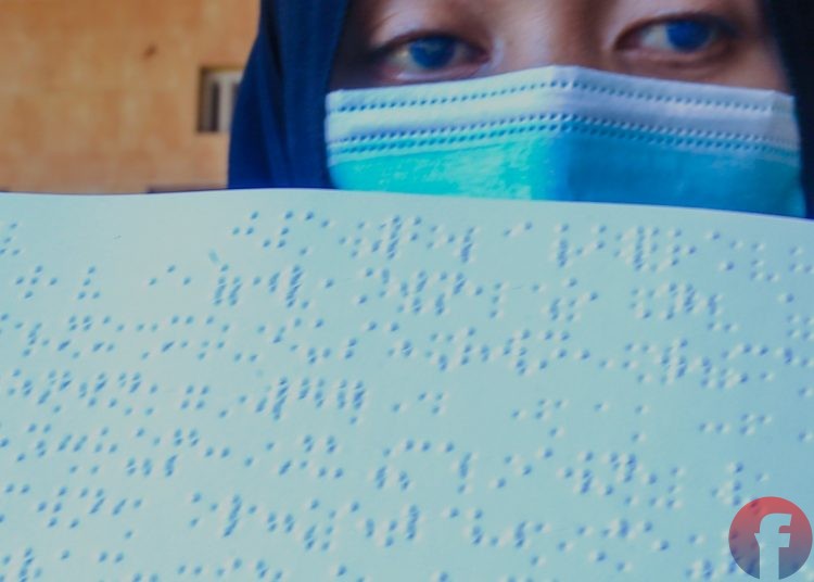 Meisari, seorang penyandang tunanetra, yang matanya kebiru- biruan menunjukkan Alquran braille yang ia baca. (matakamera/fornews.co/mushaful imam)