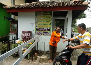 Petugas memeriksa suhu tubuh warga sebelum masuk ke kawasn Desa Mindaka, di Kabupaten Tegal, Jawa Tengah, Sabtu (13/3/2021). Desa tersebut menjadi salah satu desa percontohan PPKM Mikro tentang penerapan protokol kesehatan se-Kabupaten Tegal. (istimewa/antarafoto via kominfo)