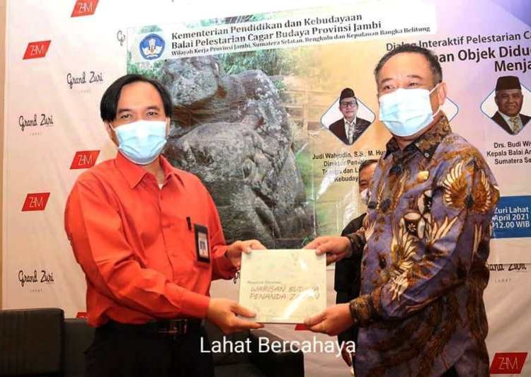 Bupati Lahat Cik Ujang menerima buku Warisan Budaya Penanda Zaman dari Kasubag TU Balai Pelestarian Cagar Budaya Provinsi Jambi Kristanto Januardi pada dialog interaktif pelestarian objek cagar budaya di Ballroom Hotel Grand Zuri Lahat, Kamis (29/4/2021). (fornews.co/kominfo lahat) 