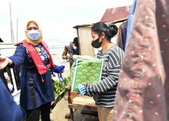 Ketua TP PKK Sumsel Febrita Lustia menyerahkan paket Sembako kepada warga di tepian Sungai Musi Kota Palembang, Selasa (4/5/2021). (fornews.co/humas provinsi sumsel)