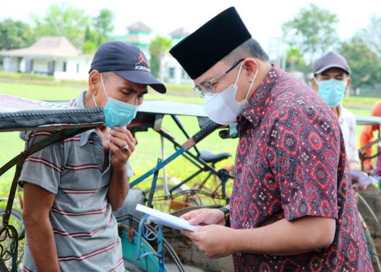 Bupati Muba Dodi Reza Alex menyerahkan THR kepada seorang tukang becak di Sekayu, Rabu (12/5/2021). (fornews.co/humas pemkab muba)