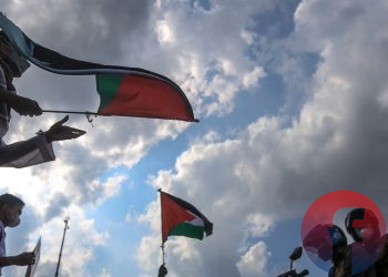 Massa membentangkan poster dan mengibarkan bendera di depan pengguna jalan yang berhenti di traffic light. (matakamera/fornews.co/mushaful imam)