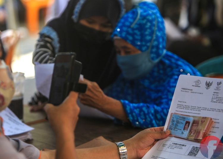 Petugas memfoto berkas dan penerima Bantuan Sosial Tunai di Kantor Pos Pusat Jalan Merdeka Palembang, Senin (26/7/2021). (fornews.co/mushaful imam)