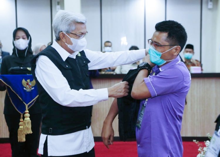 Wakil Gubernur Sumsel, Mawardi Yahya, memasangkan seragam kepada petugas pemantauan dan pemeriksaan hewan kurban, saat pelepasan di Graha Bina Praja, Kamis (1/7/21). (fornews.co/humas pemprov sumsel)