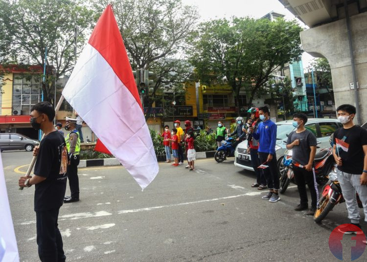 Pengendara yang melintas di Jalan Jenderal Sudirman Simpang 4 Charitas berhenti sejenak untuk menghormati detik proklamsi, Selasa (17/8/2021). (fornews.co/mushaful imam)