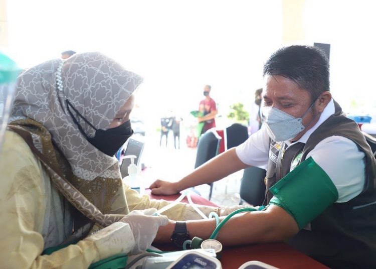 Gubernur Sumsel, Herman Deru, tengah memeriksa tensi darah di sela-sela pemberian vaksinasi untuk driver ojek online di Politeknik Pariwisata (Poltekpar) Palembang, Kamis (9/9/2021). (fornews.co/humas pemprov sumsel)