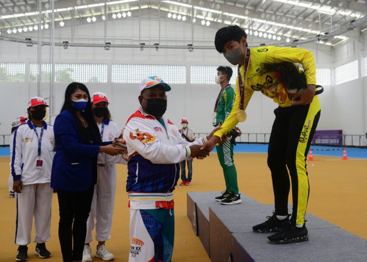 Pengalungan Medali Emas Oleh Gubernur Papua, Lukas Enembe kepada Atlet sepatu roda putra Dave Emmanuel Abel, nomor ITT 100 M Final - Putra PON XX Papua, Gedung Konselir Klemen Tinal Roller Sport Stadiium, Kota Jayapura, Senin (27/09/2021), (fornews.co/Foto: PB PON XX PAPUA/Ronaldy Irfak)