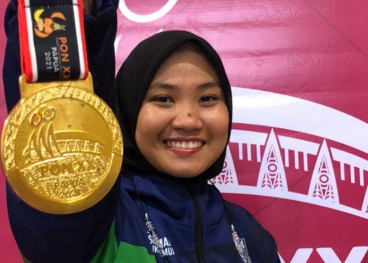Atlet Pencak Silat Sumsel, Fransiska Sandra Dewi, memamerkan keping medali emas kelas tanding F 70-75 kg putri, pada final di venue silat GOR Toware, Sentani, Papua, Selasa (12/10/2021). (fornews.co/ist)