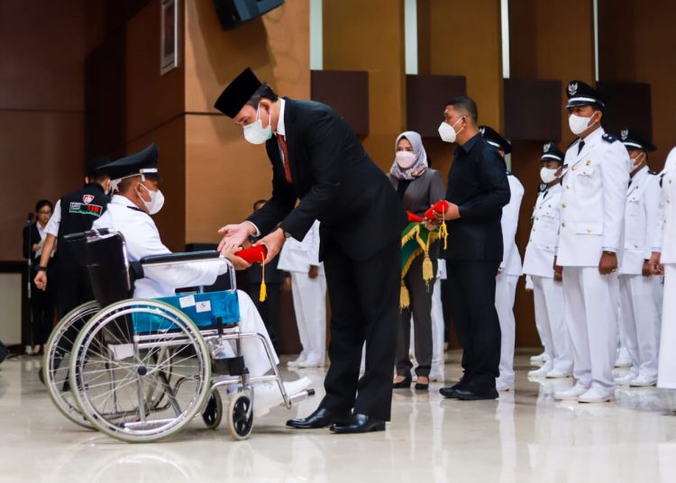 Plt Bupati Muba, Beni Hernedi saat memberikan SK kepada salah satu Kades terpilih yang menggunakan kursi roda saat pelantikan dan pengambilan sumpah Kades di Opprom Pemkab Muba, Senin (27/12/2021). (fornews.co/humas pemkab muba)