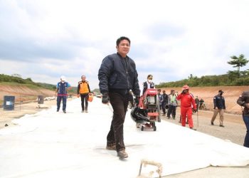 Sambil menenteng heml, Gubernur Sumsel, Herman Deru, melihat langsung kondisi pengerjaan pembangunan Jalan Tol Kapal – Betung di arah Jembatan Musi II sisi Gandus, Sabtu (9/4/2022). (fornews.co/humas pemprov sumsel)