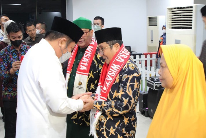 Gubernur Sumsel, Herman Deru melakukan penyematan tanda peserta dan pemasangan syal kepada perwakikan jamaah umrah di Bandara SMB 2 Palembang, Kamis (26/5/2022). (fornews.co/humas pemprov sumsel)
