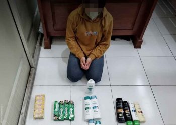 WN tertunduk malu setelah mengeluarkan seluruh isi dalam sweater dan celana jeans yang dipakai untuk menyembunyikan barang-barang yang diambil di Toko WN, Gedangan, Sentolo, Kulon Progo pada Rabu (8/6/2022). (foto fornews.co/polsek sentolo)