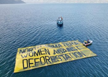 Banner besar bertuliskan ‘Perempuan Sumatera Utara Lawan Deforestasi’ yang dibentangkan aktivis serta para perempuan Desa Toba, Rabu (20/7/2022). (fornews.co/ist)