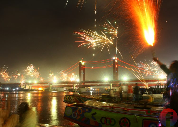 Warga Palembang sedang menikmati kembang api di atas kapal pinggiran Sungai Musi Palembang, Sabtu (31/12/2022). (fornews.co/Wahyu Rahmanto)