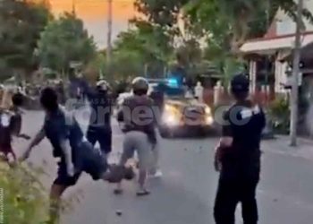 TERLIHAT mobil polisi berusaha melerai aksi saling lempar batu dari kedua kelompok bertikai di seputar Stadion Mandala Krida. (foto fornews.co/adam)