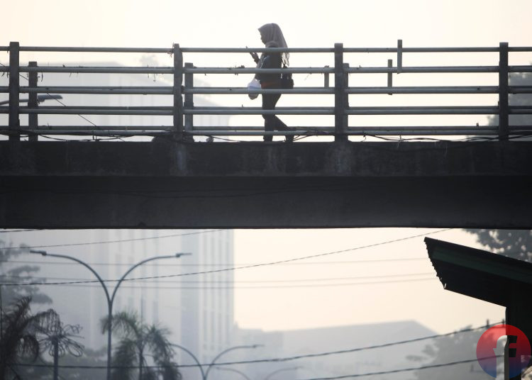 Tampak seorang waga hendak menuju ke tempat bekerja di Tengah kondisi cuaca pagi Kota Palembang yang sudah tercemar polusi asap dari karhutla. (fornews.co/mushaful imam)