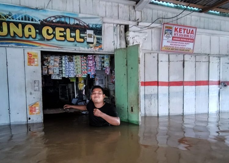 Pedagang di kawsasan Kecamatan Rupit tidak bisa berbuat banyak dan hanya bisa tersenyum, saat masih terendam banjir besar di Muratara. (fornews.co/ist)