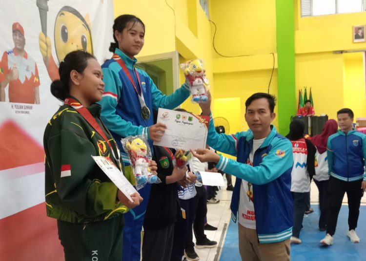 Sekretaris Umum KONI OKI, Iskandar Fuad mengalungkan medali emas kepada salah satu atlet Gulat putri, di venue Gulat Porprov XV Sumsel 2025, Senin (20/10/2025). (fornews.co/ist)