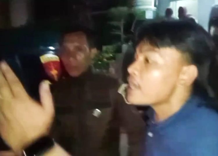 Oknum yang diduga salah satu kolega tersangka WS, saat mencoba menghentikan Wartawan Foto Antara, Nova Wahyudi, untuk mengambil gambar di mobil tahanan di halaman Kantor Kejati Sumsel, Senin (17/11/2025) malam. (fornews.co/tangkap layar)