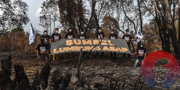Sejumlah aktivis lingkungan WALHI Sumsel membentangkan spanduk di belas kebakaran lahan di Dusun 3, Desa Arisan Jaya, Kecamatan Pemulutan Barat, Kabupaten Ogan lir, Sumsel, Jumat (14/8/2026). (fornews.co/foto: Mushaful Imam)