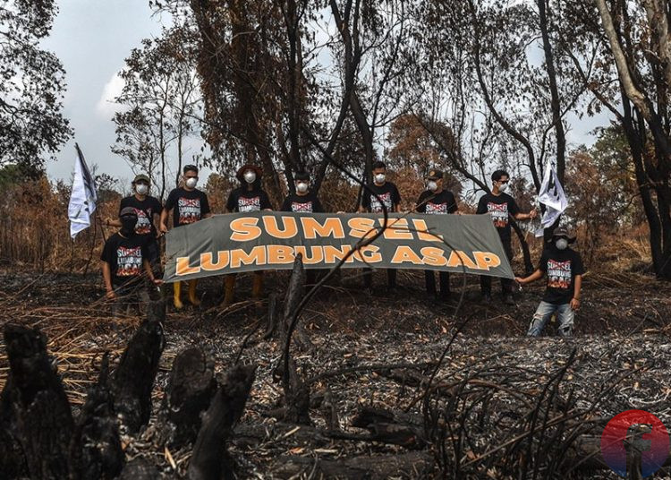 Sejumlah aktivis lingkungan WALHI Sumsel membentangkan spanduk di belas kebakaran lahan di Dusun 3, Desa Arisan Jaya, Kecamatan Pemulutan Barat, Kabupaten Ogan lir, Sumsel, Jumat (14/8/2026). (fornews.co/foto: Mushaful Imam)