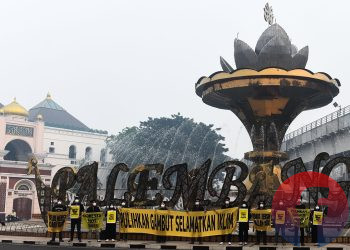 Relawan Tim Cegah Api, saat mengirim pesan 'Belum Merdeka dari Asap' dan 'Udara Bersih adalah Hak' di depan Jembatan Ampera, pada Rabu, (7/10/2026). (fornews.co/foto: Mushaful Imam)